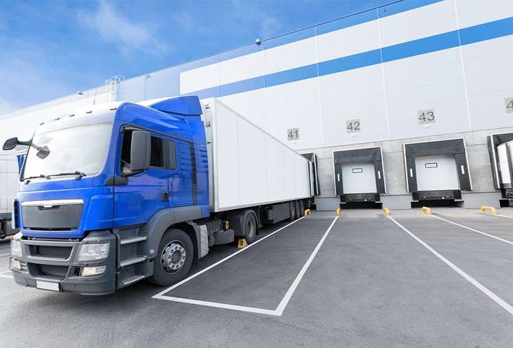 Colliers National Industrial Report, Industrial Building with a truck unloading through dock doors.